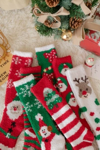 Makroaufnahme von flauschigen Korallenvlies-Weihnachtssocken mit festlichen Mustern