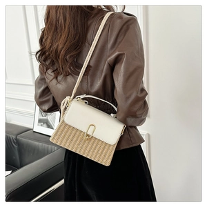 Detail of woven straw crossbody bag featuring white leather trim and a rope strap