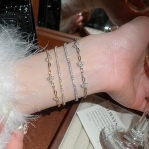 Detailed view of layered 18k gold plated flower bracelets with zircons on a wrist