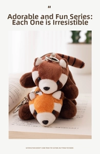 Close-up of adorable brown and orange panda plush keychain charms on an open book