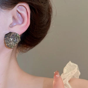 Close-up of irregular grey resin stud earrings with a sparkling mineral texture