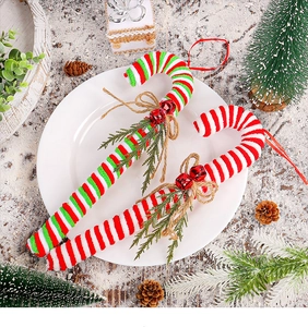 Detail of knitted Christmas candy cane hanging with jute bow, bell and pine needles