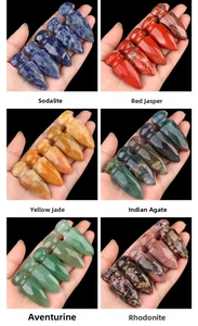 Macro shot of assorted natural crystal arrowheads held by hand against black background