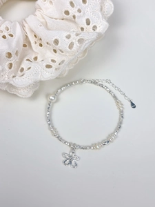 Detailed macro view of S925 sterling silver flower charm and freshwater pearl bracelet
