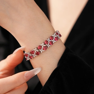 Detailansicht eines luxuriösen Doppelarmbands mit rotem Zirkon und Silberblüten-Akzenten