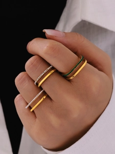 Close-up of gold-plated rings set with green emerald and white zircon gemstones