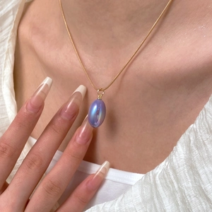 Detailed close-up of colorful pear-shaped teardrop pendant on a gold necklace for women