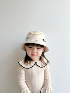 Close-up of cream kids fisherman hat with colorful bows and knit sweater detail