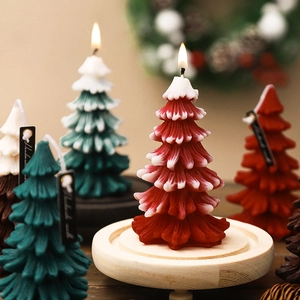 Handmade Christmas tree shaped scented candle in festive red on a rustic wooden tray