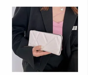 Detail of white quilted faux leather wallet with geometric pattern and metal zipper closure