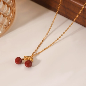 Collana in acciaio inossidabile placcato oro 18K con ciondolo a ciliegia rossa su sfondo bianco