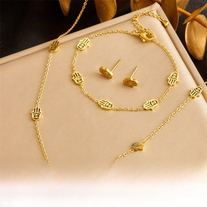 Detailed set of gold-plated Hamsa Hand necklace, bracelet and earrings on a jewelry box