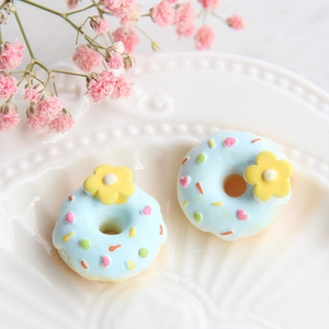 Makro-Detail von blauem Harz-Donut mit gelber Blume und Streuseln auf weißem Teller