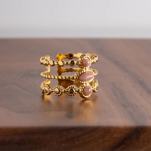 French vintage adjustable gold stainless steel ring with pink stones on a wood surface
