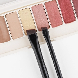 Dual angled eyeliner and eyebrow brushes with black textured handles and sharp fiber bristles