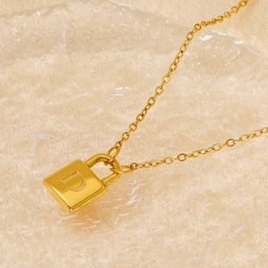 Macro view of gold stainless steel padlock pendant with engraved letter D on chain