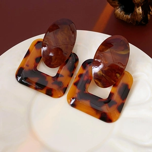 Detailed macro view of retro tortoiseshell resin earrings on a vintage white plate