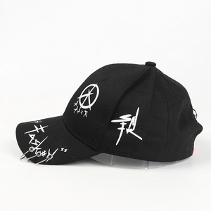 Detail of black cotton baseball cap with white graffiti art and three metal rings on the brim