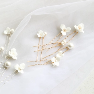 Detailed shot of 6 gold U-shaped bridal hair pins with ceramic flowers and white pearls