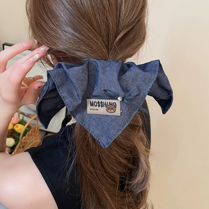 Detailed view of blue denim bow hair claw with bear patch and MOSSHINO text