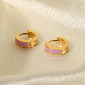 Detail of gold titanium steel hoop earrings with pink enamel on a silk background