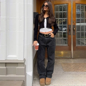 Draußen-Aufnahme einer Frau mit schwarzer Strickjacke und grauer Wide-Leg-Jeans