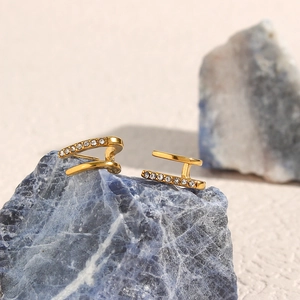 Detailed shot of gold double-layer earrings with cubic zirconia on a natural blue stone