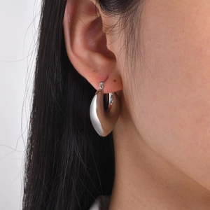 Macro detail of chunky hollow silver hoop earrings in a high-polished mirror finish