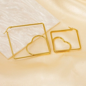 Close-up of gold heart square earrings on elegant champagne satin and marble background