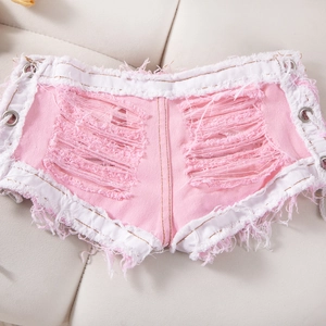 Detalle de pantalones cortos de mezclilla rosa con flecos rotos y ojales metálicos