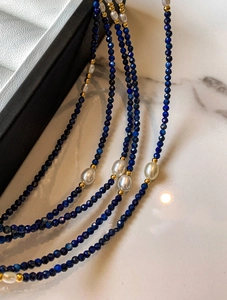 Vue détaillée des perles de Lapis-Lazuli avec perles blanches et perles en métal doré
