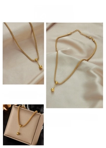Detailed macro view of a gold-plated mesh chain necklace with double bead pendants