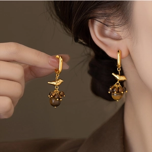 Detail of bird-shaped earring with gold plating and brown tiger eye stone beads