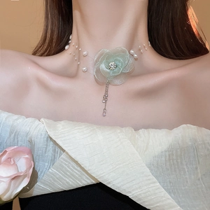 Close-up of a light green fabric flower choker with pearls and crystals on a model