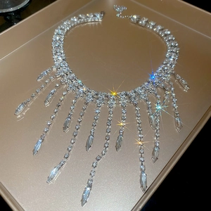 Detailed macro shot of silver tassel necklace with rhinestones on a gold tray