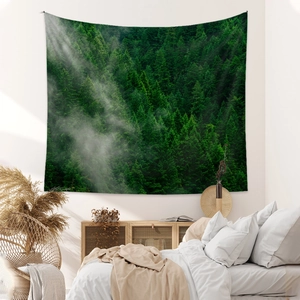 Modern wall tapestry featuring deep green forest pine trees and misty mountain landscape