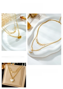 Close-up of double layer gold necklace with hollow heart links and a white pearl heart pendant