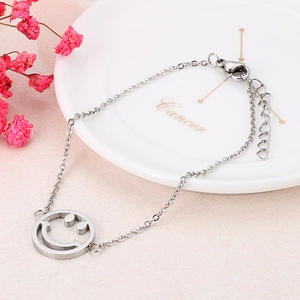 Detail of silver stainless steel chain bracelet with a hollow smiley face pendant charm