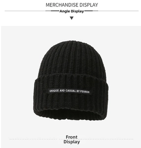Detailed view of the black ribbed knit beanie featuring a rectangular woven patch label