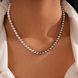 Close-up of minimalist silver-grey beaded necklace worn on neck with white shirt