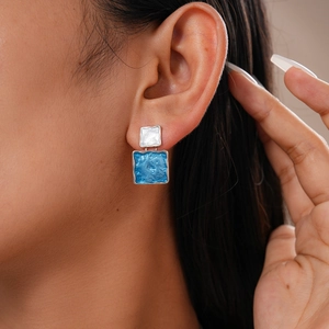 Close-up of geometric square earrings with textured blue and silver double layers