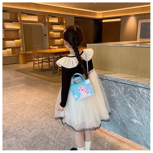 Modern kid's blue handbag with pink unicorn print shown being carried in a bright hall