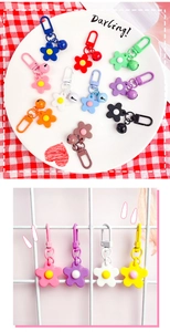 Detailed view of colorful flower keychains with bells and metal carabiners on a white grid