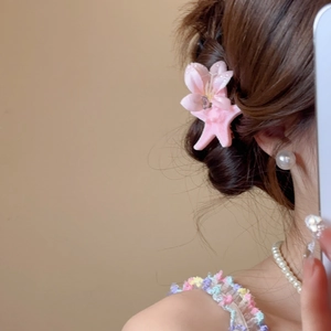 Detail of pink floral and starfish clip worn on head for vacation hairstyle