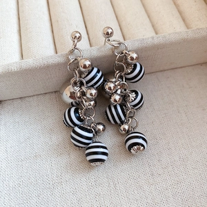 Detail of silver chain earrings with polished black and white striped round beads