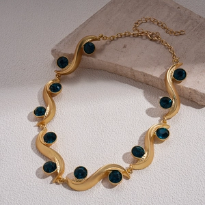 Detail of gold wavy sweater chain with deep blue round crystals and lobster clasp