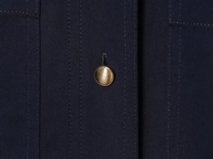Gros plan sur une robe chemise en sergé bleu marine avec un bouton doré texturé