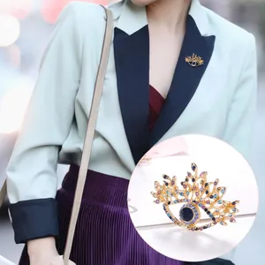 Macro detail of vintage eye brooch with blue gemstone and colorful crystals on lapel
