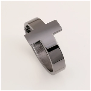 Detail of a minimalist black metal cross cuff bracelet with a sleek mirror-like finish