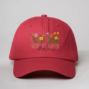 Close-up of red cotton baseball cap featuring floral embroidery and GOD IS GOOD text